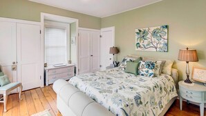 A bedroom with a large bed, two bedside tables, a bench, and a wardrobe.