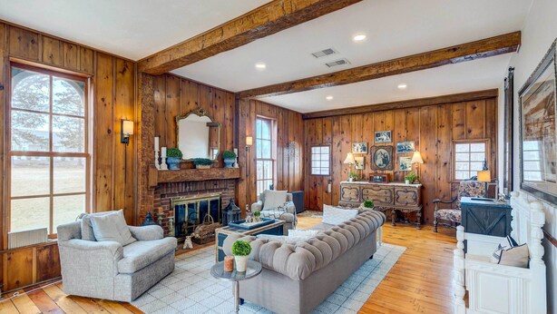 A spacious living room with wooden walls, a fireplace, and a large sectional sofa.