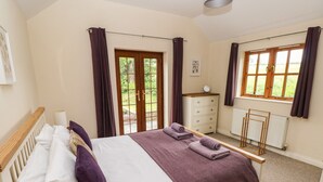 A bedroom with a bed, a dresser, a radiator, and a window with curtains. - Ty Rhosyn (Haverfordwest)