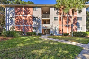 A modern building with a central entrance, surrounded by well-maintained lawns and palm trees.