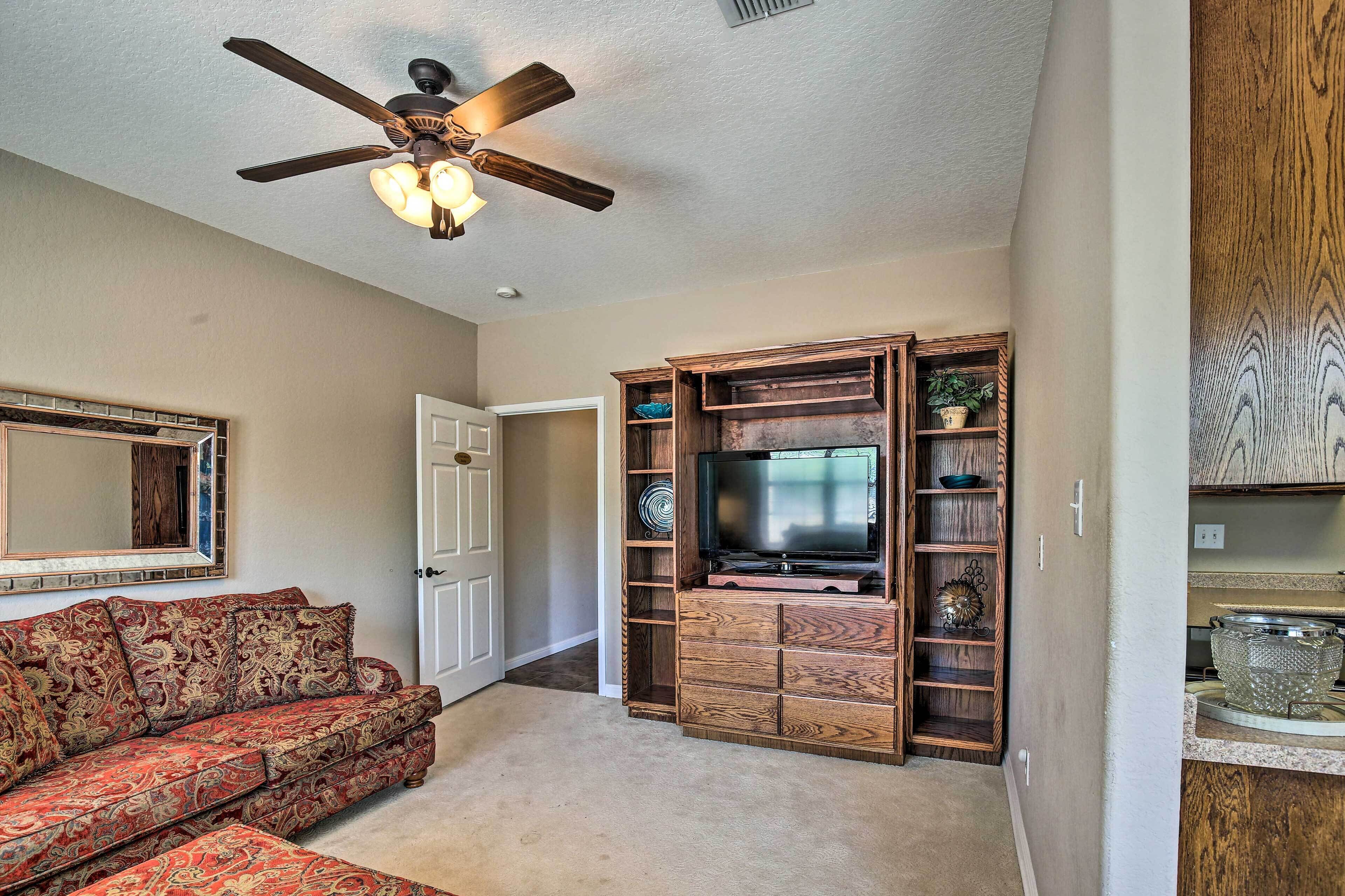 A living room with a sofa, TV stand, and ceiling fan.