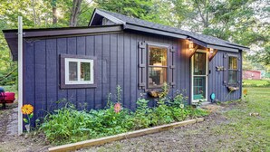 A small, dark wooden cabin with a sloped roof, large windows, and a front door. - Lake Access & Kayaks: Gladwin Cottage Near Golfing (Gladwin)