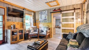 A cozy cabin interior with a wooden ceiling, a dining area, and a living room with a sofa and chairs. - Lake Access & Kayaks: Gladwin Cottage Near Golfing (Gladwin)