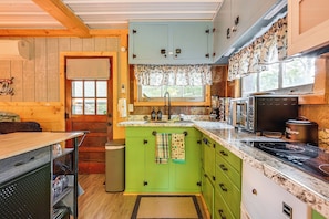A compact kitchen with green cabinets, a granite countertop, and a built-in stove. - Lake Access & Kayaks: Gladwin Cottage Near Golfing (Gladwin)