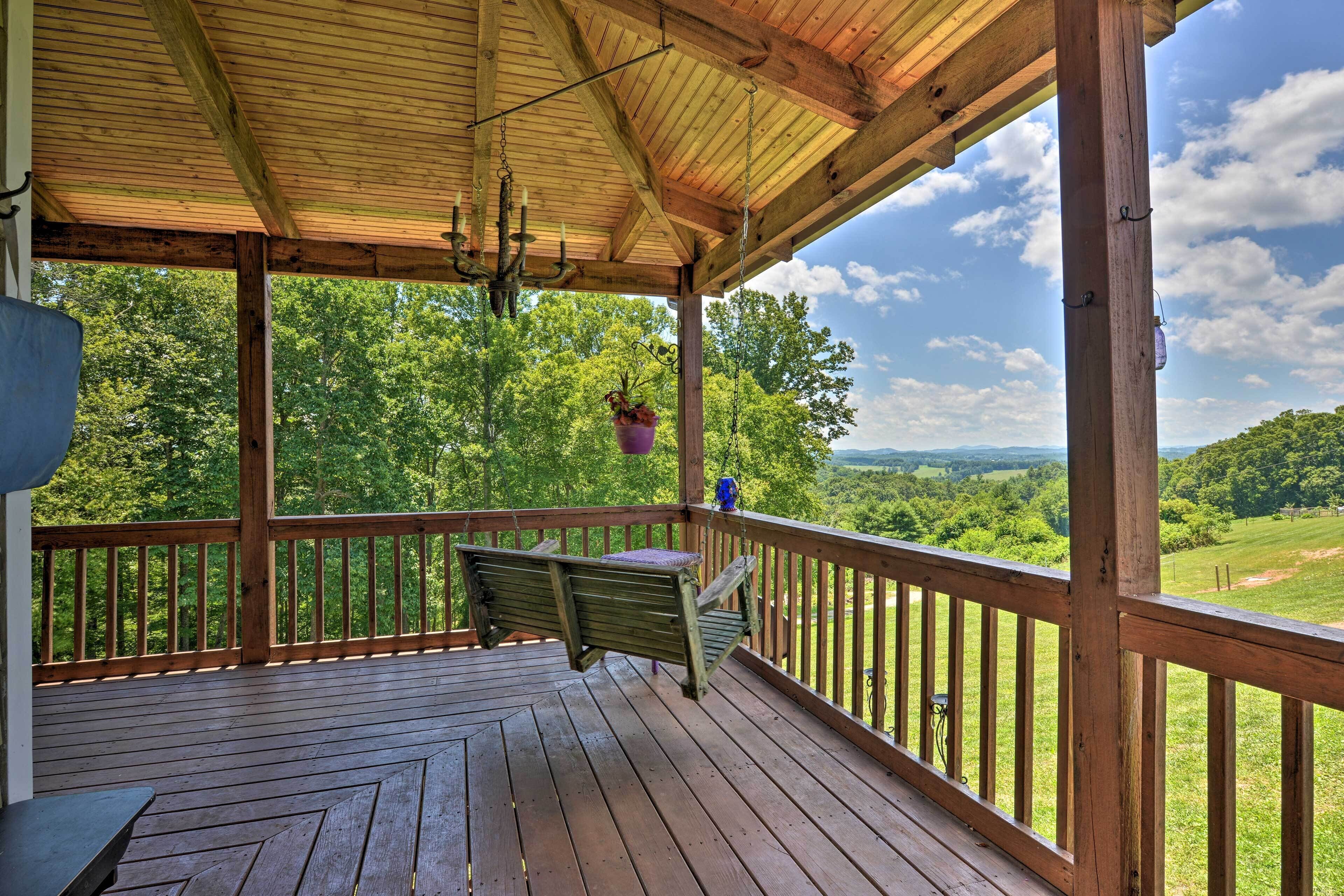 Une terrasse en bois avec un banc et des plantes suspendues, offrant une vue sur un paysage verdoyant et luxuriant.