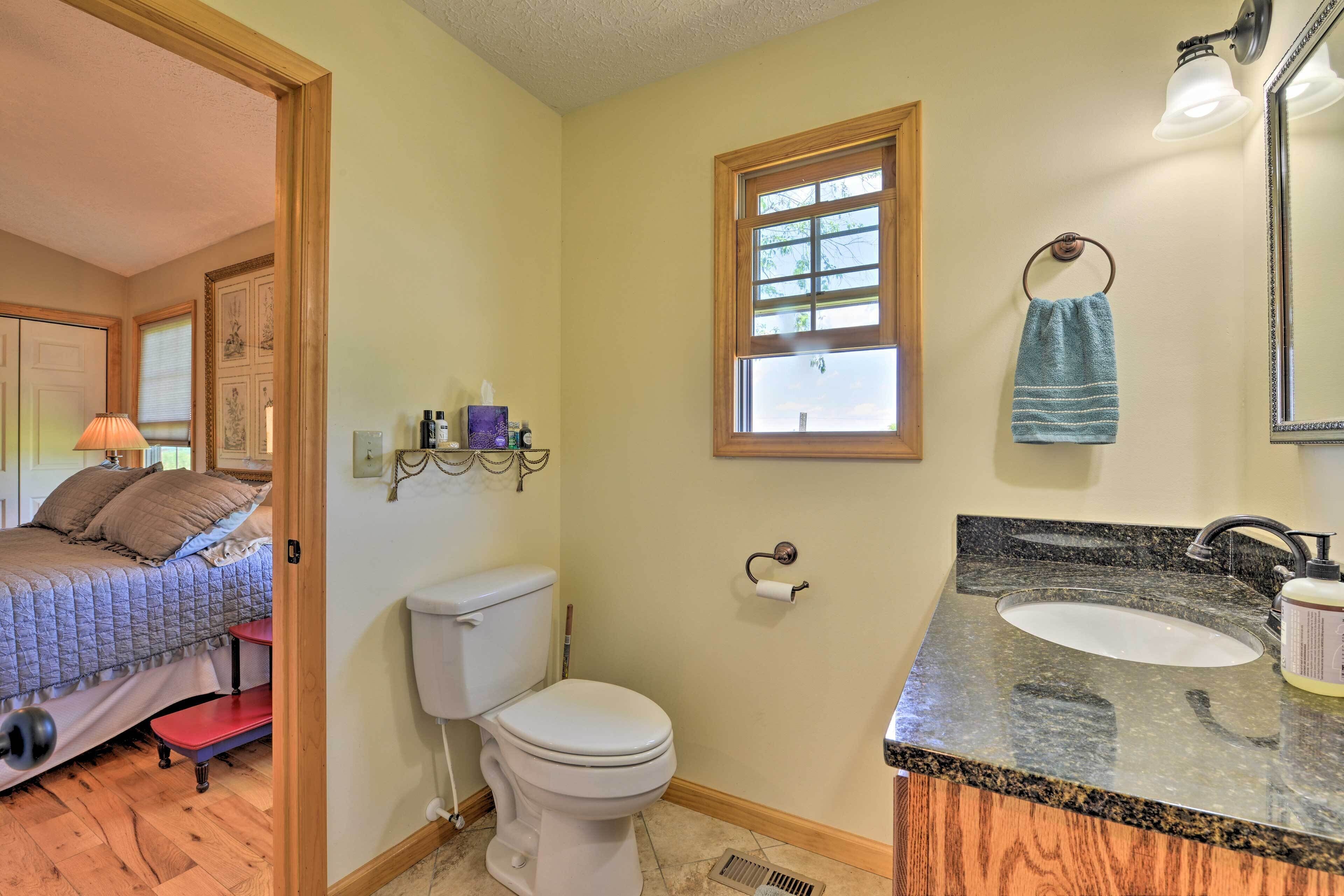 A bathroom with a toilet, sink, and window.