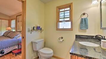 A bathroom with a toilet, sink, and window.