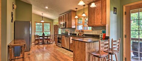 A spacious kitchen with wooden cabinets, a central island with bar stools, and a dining area with a table and chairs.