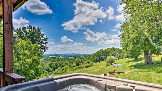 Ein Whirlpool mit herrlichem Blick auf eine üppige grüne Landschaft und Berge im Hintergrund.