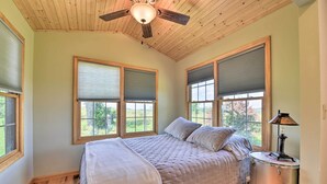 Ein Schlafzimmer mit einem Bett, einem Deckenventilator, großen Fenstern und einem Schlagzeug.