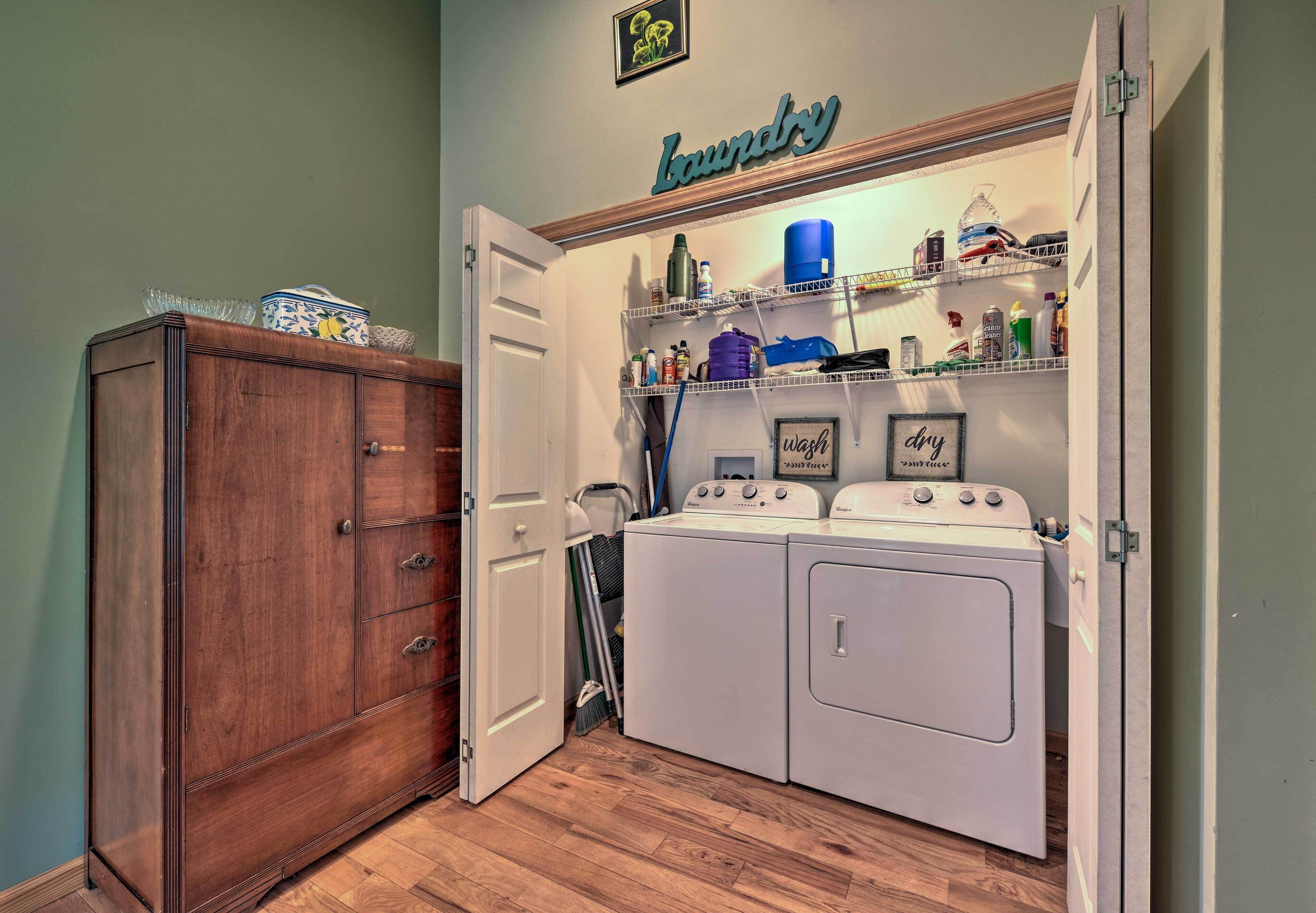 A laundry room with a wooden cabinet, a washing machine, and a shelf with various laundry supplies.