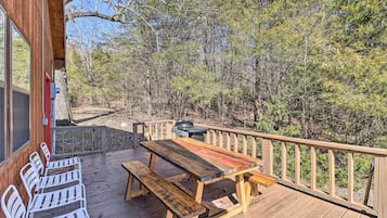 A wooden deck with a picnic table and benches, surrounded by trees.