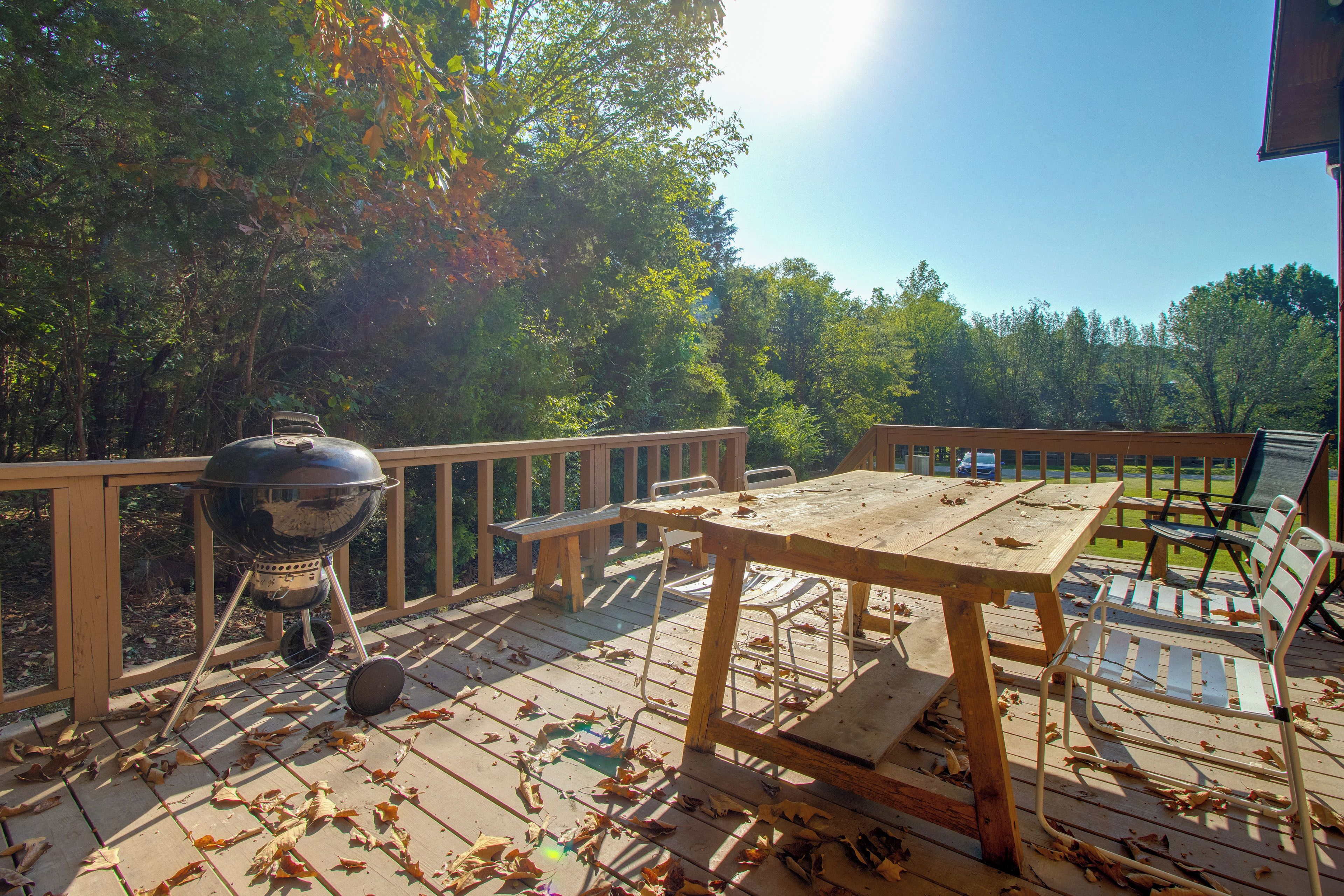 A wooden deck with a barbecue grill, picnic table, and chairs.