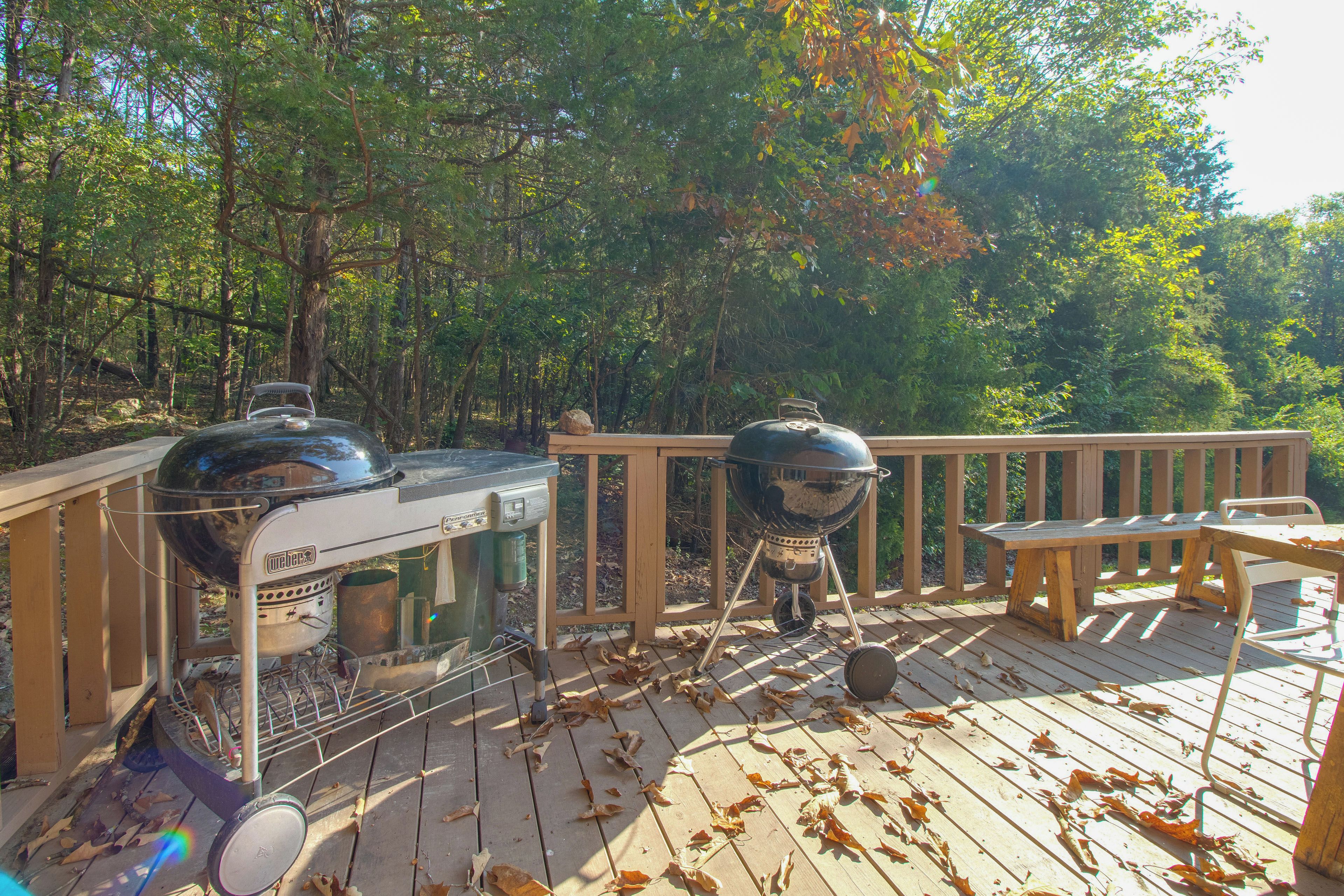 A wooden deck with two Weber grills and a picnic table.
