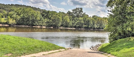 A dirt path leading to a body of water surrounded by green grass and trees.