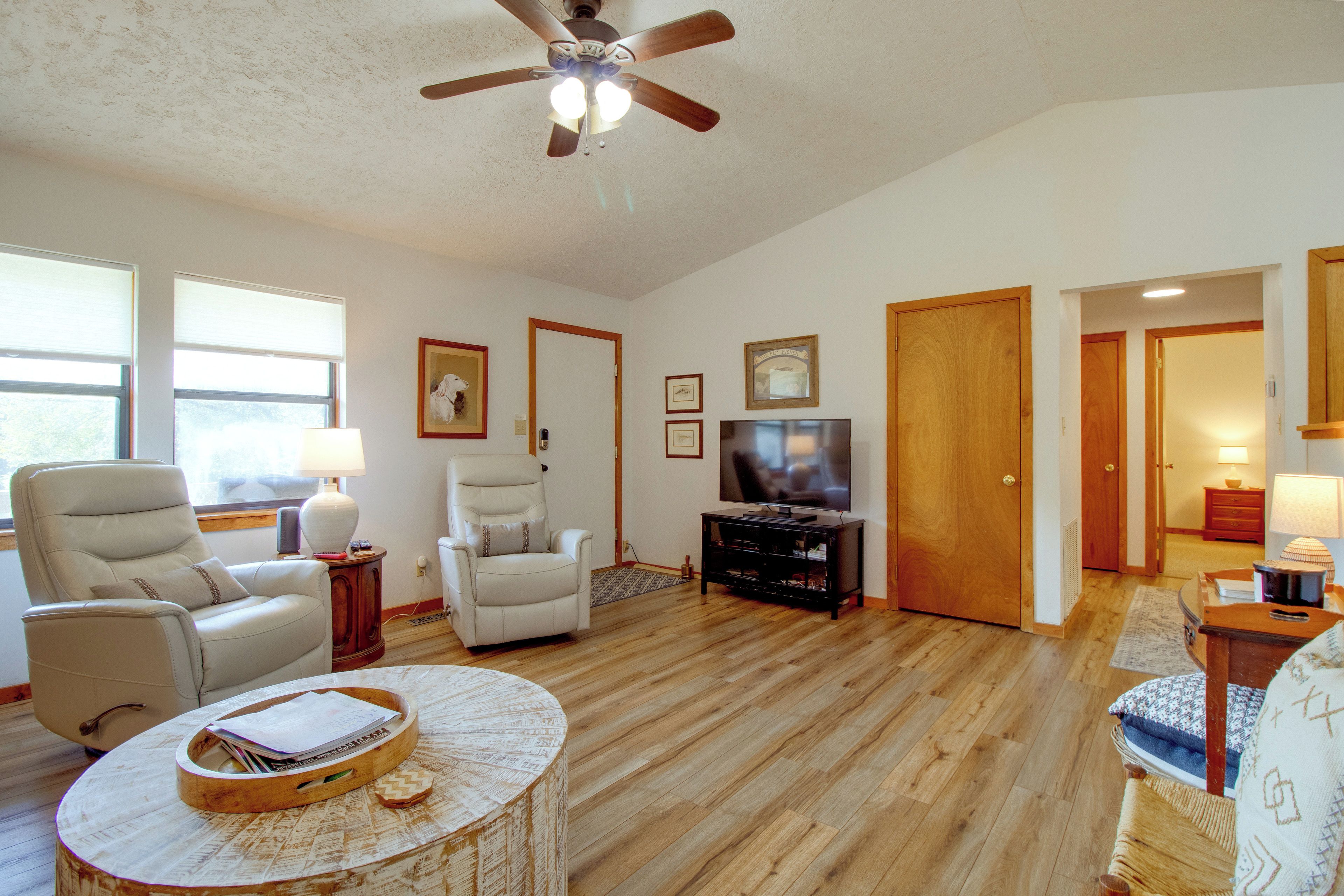 A living room with a ceiling fan, a television on a wooden stand, and a fireplace.