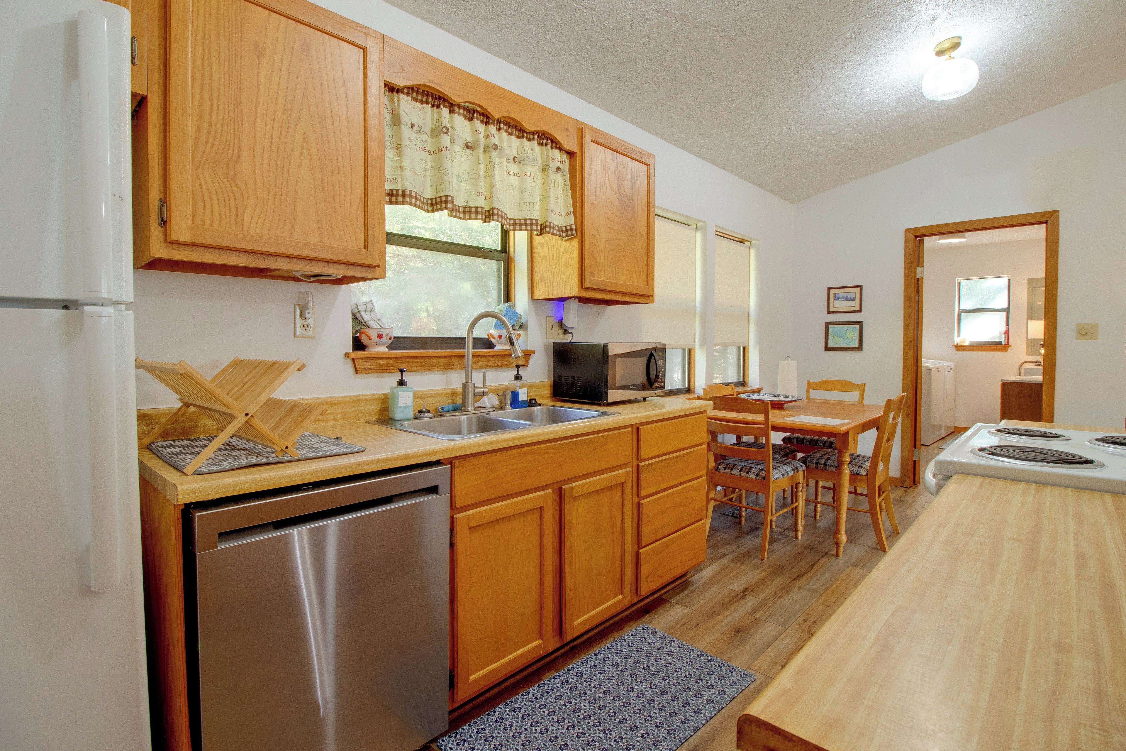 A compact kitchen with wooden cabinets, a stainless steel dishwasher, a microwave, and a sink.