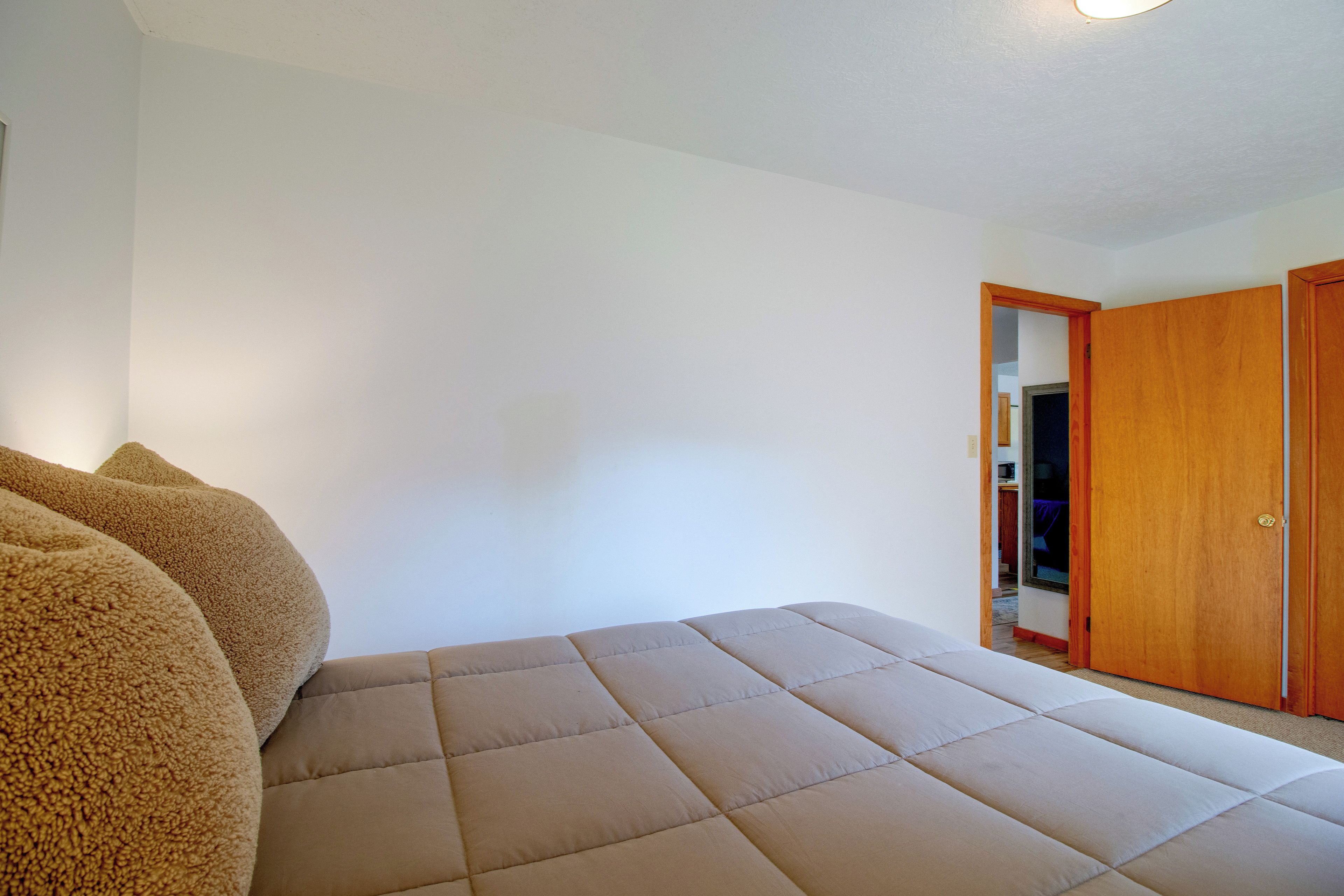 Ein Schlafzimmer mit Bett, Kleiderschrank und einer Tür zu einem anderen Raum.