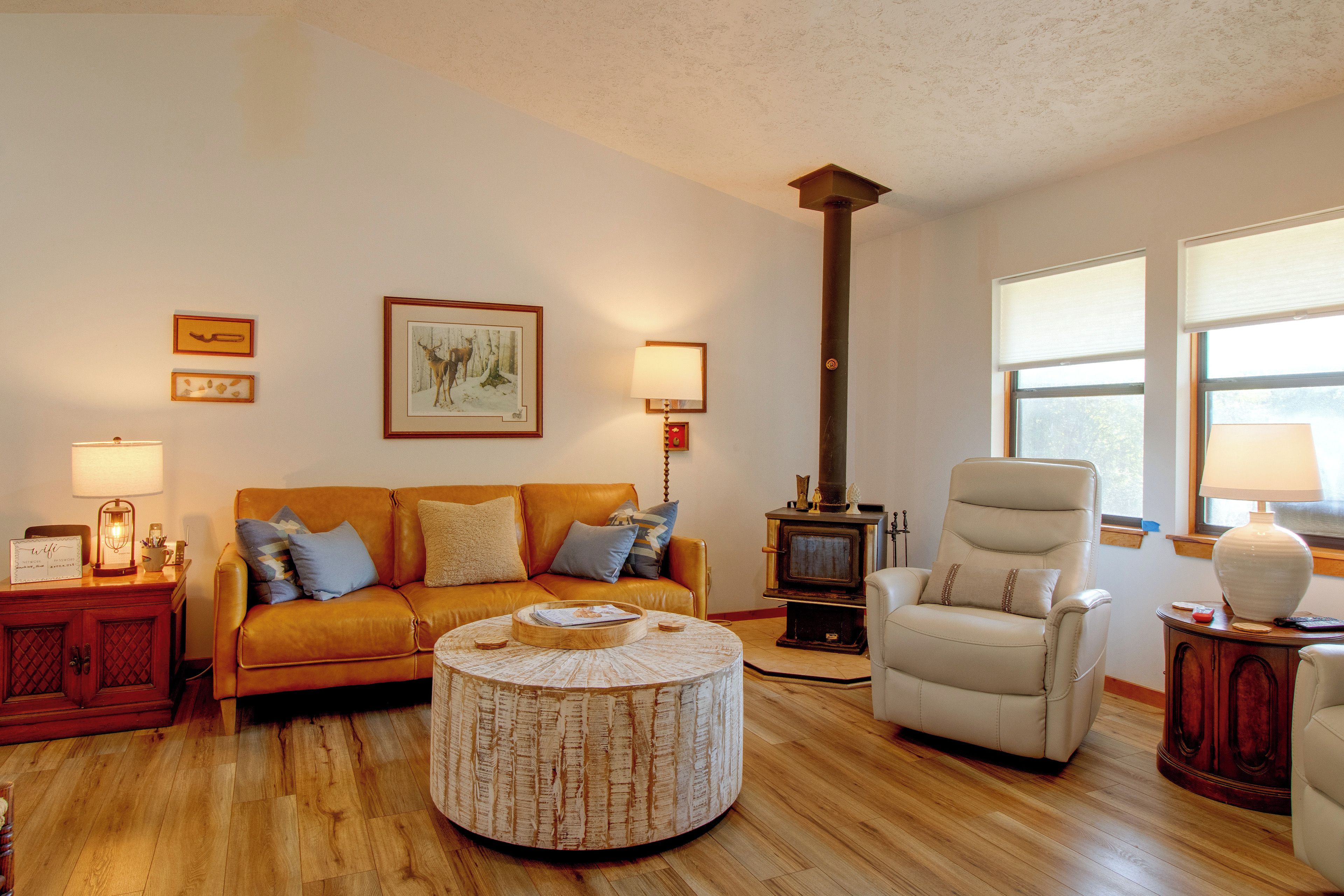 A living room with a sofa, armchair, round coffee table, and a fireplace.