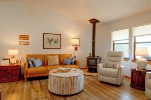 A living room with a sofa, armchair, round coffee table, and a fireplace. - Walk to White River: Home w/ Deck in Flippin! (Flippin)