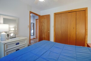 Un dormitorio con cama, cómoda con espejo y armario de madera.