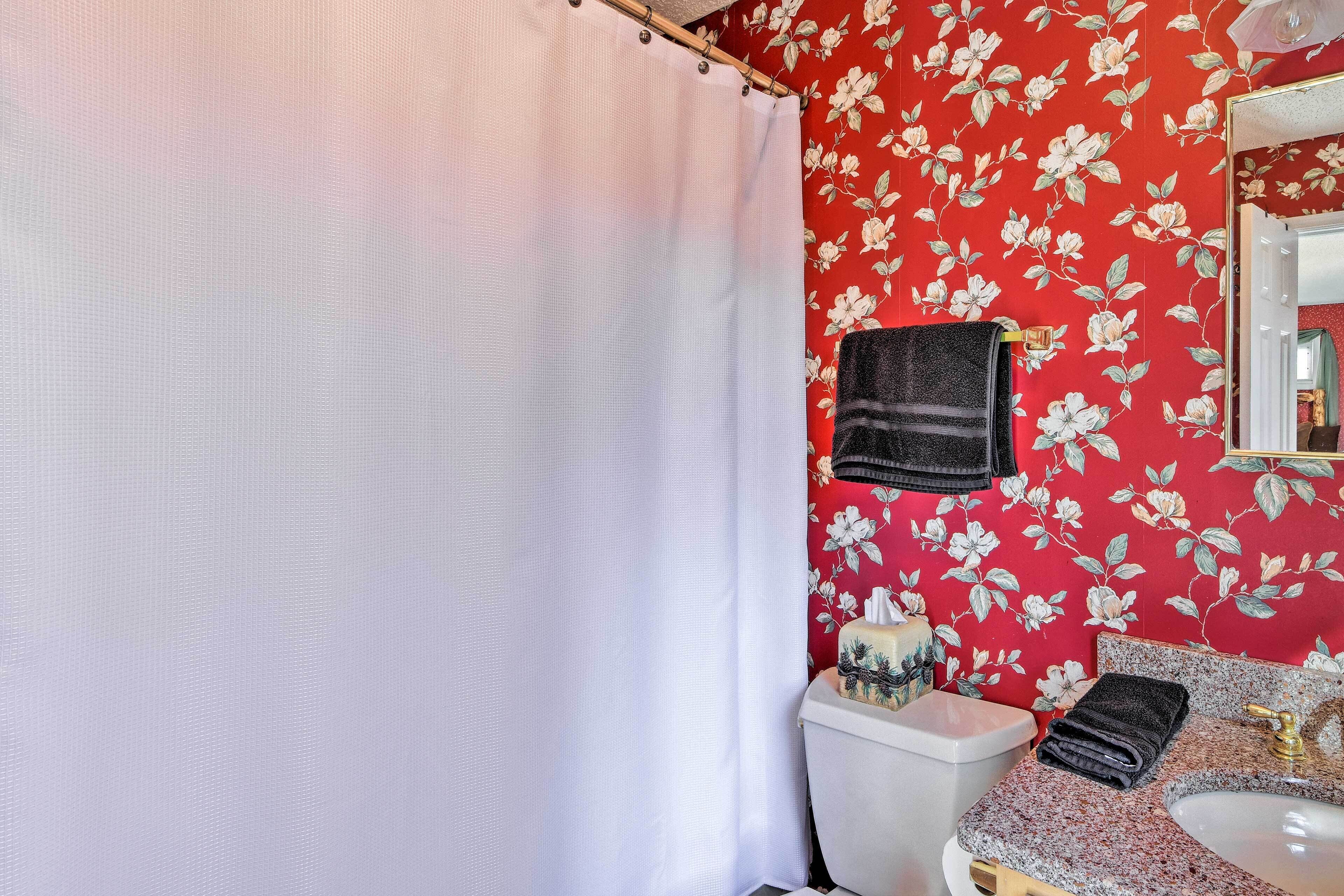 Une salle de bain avec un rideau de douche, des toilettes, un lavabo et un miroir.