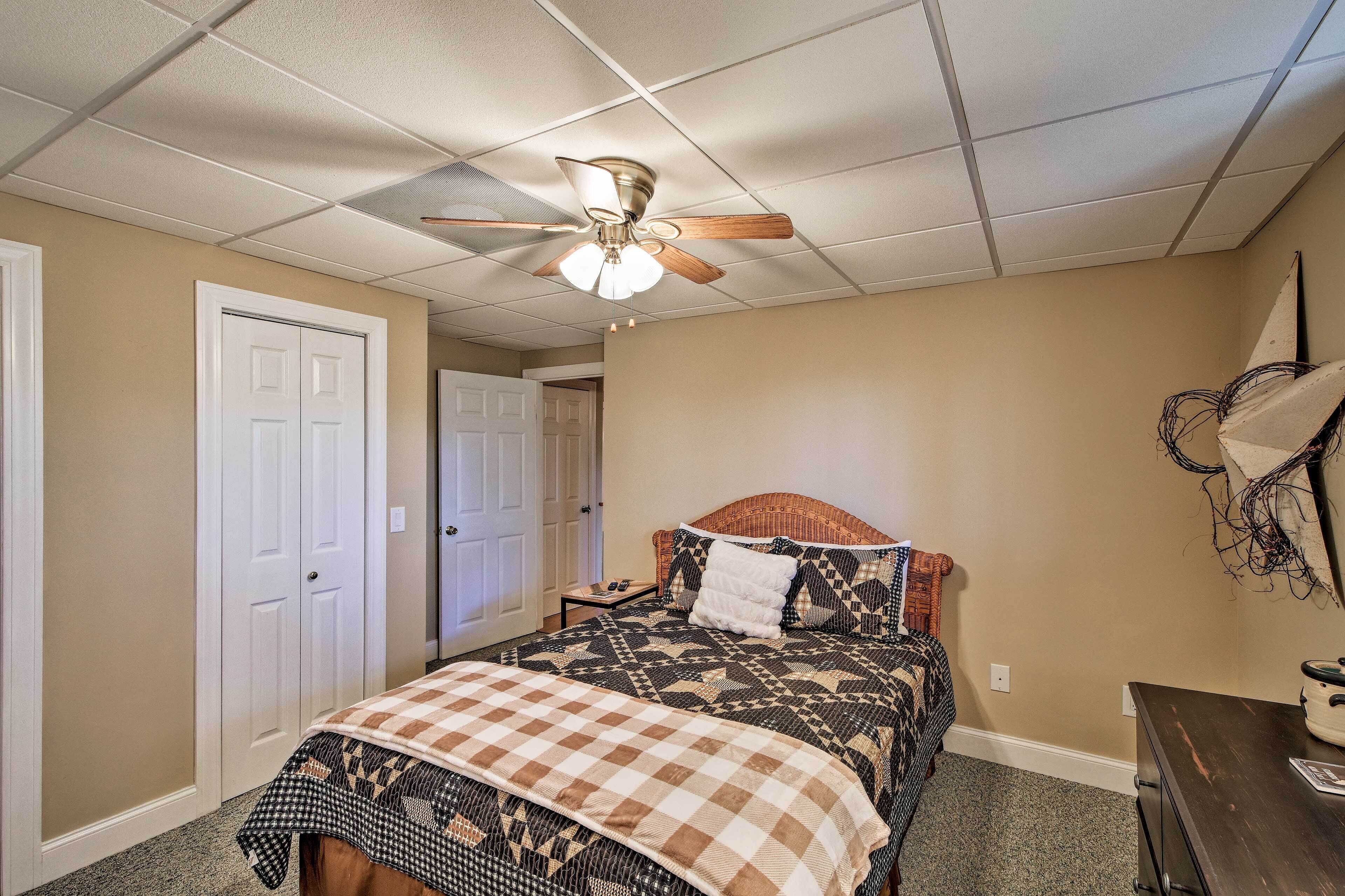 A bedroom with a bed, a ceiling fan, a dresser, and a door.