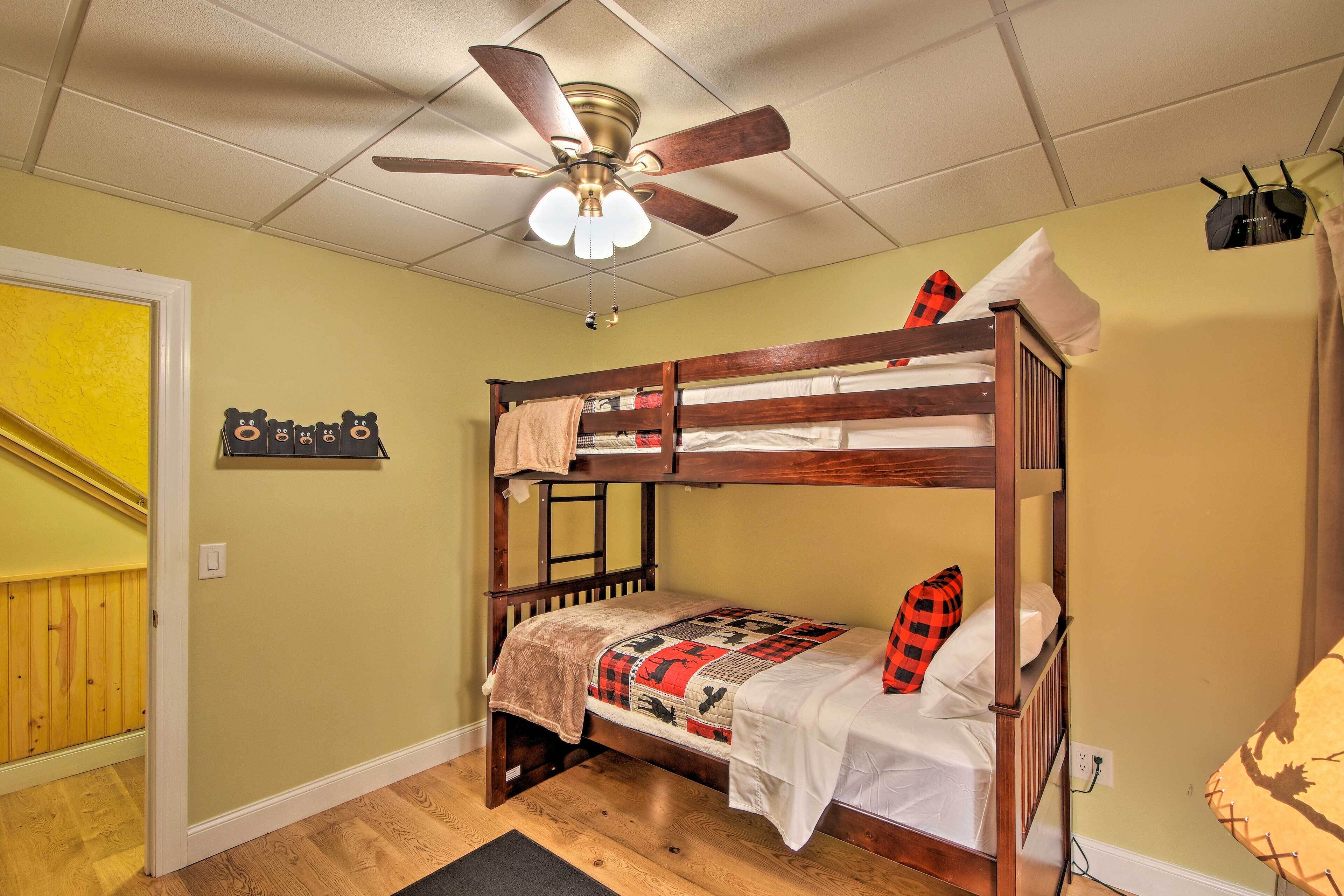 Habitación con literas, ventilador de techo, colcha y estante en la pared.