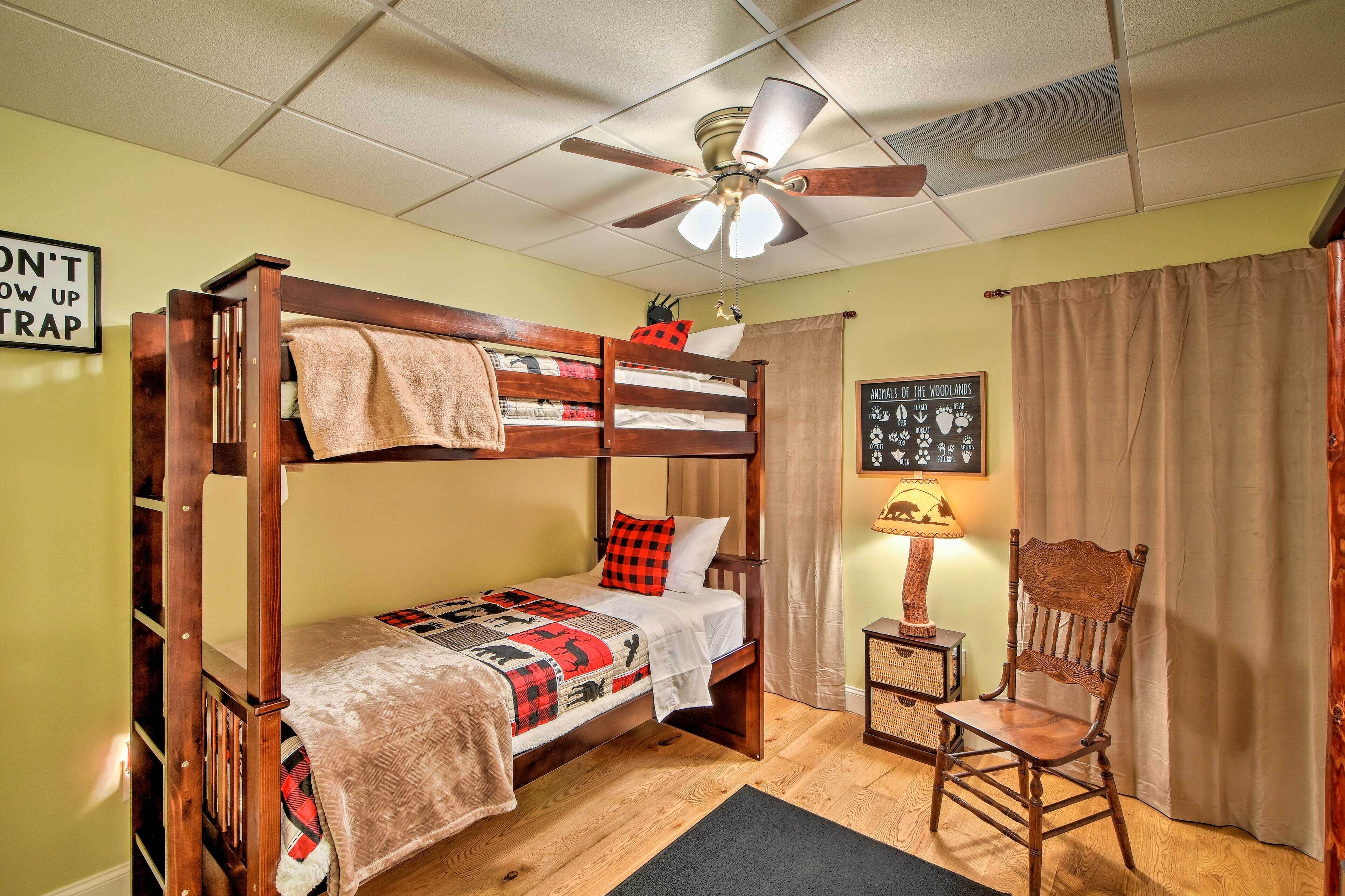 A bunk bed room with a ceiling fan, a chair, and a wall sign.