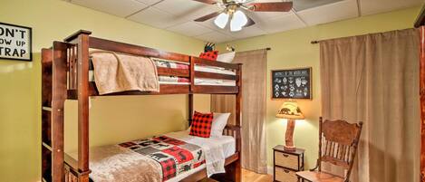 A bunk bed room with a ceiling fan, a chair, and a wall sign.