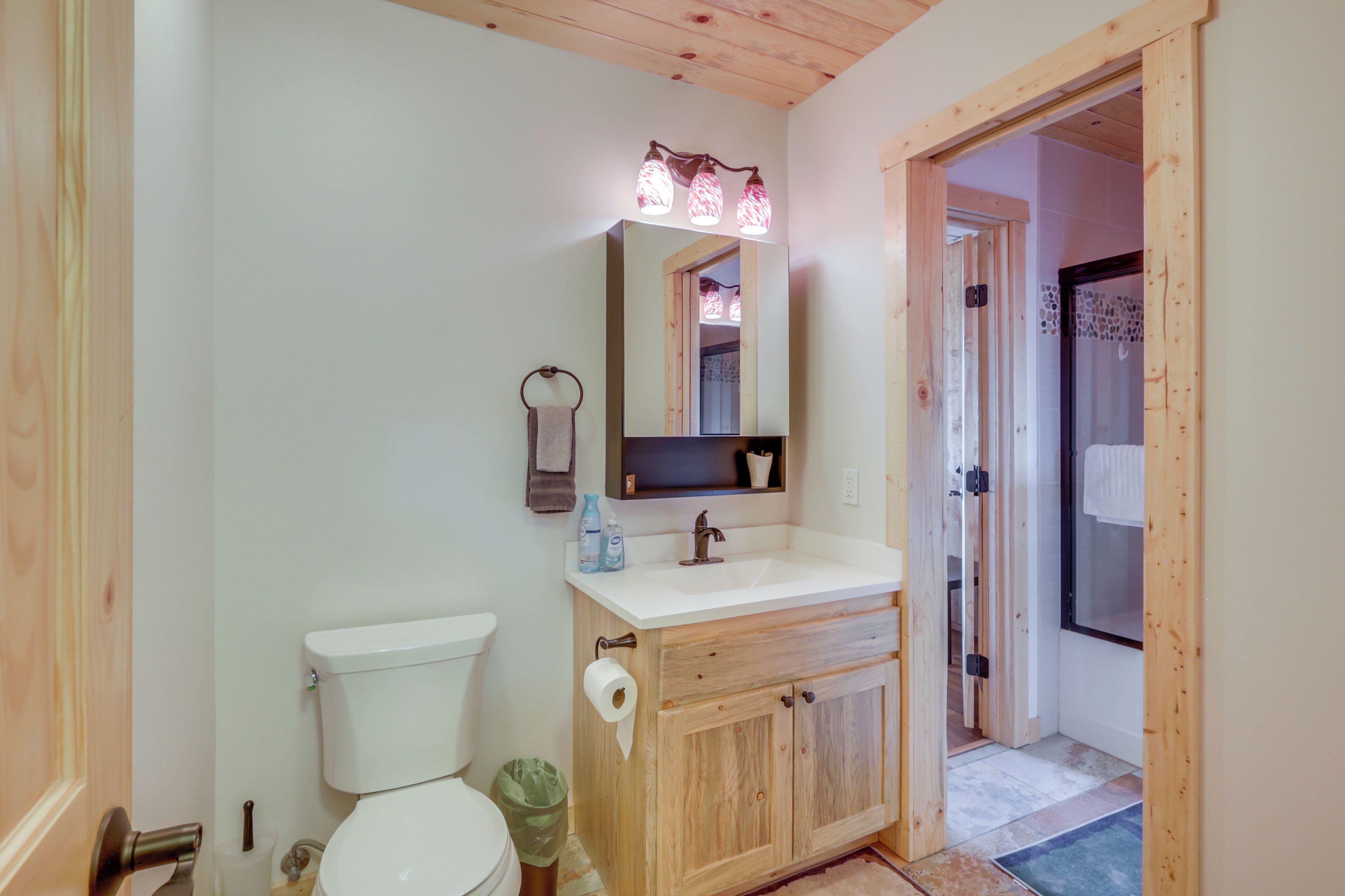 A bathroom with a wooden vanity, a white sink, a mirror above the sink, and a toilet.