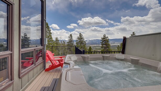 Un bain à remous sur une terrasse offrant une vue panoramique sur les montagnes.