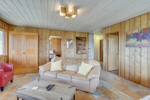Ein gemütliches Wohnzimmer mit einem beigen Ledersofa, einem Couchtisch und Holzwänden.
