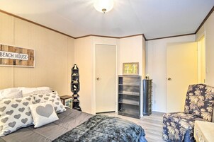 Un dormitorio con una cama, una silla, un tocador y una puerta.