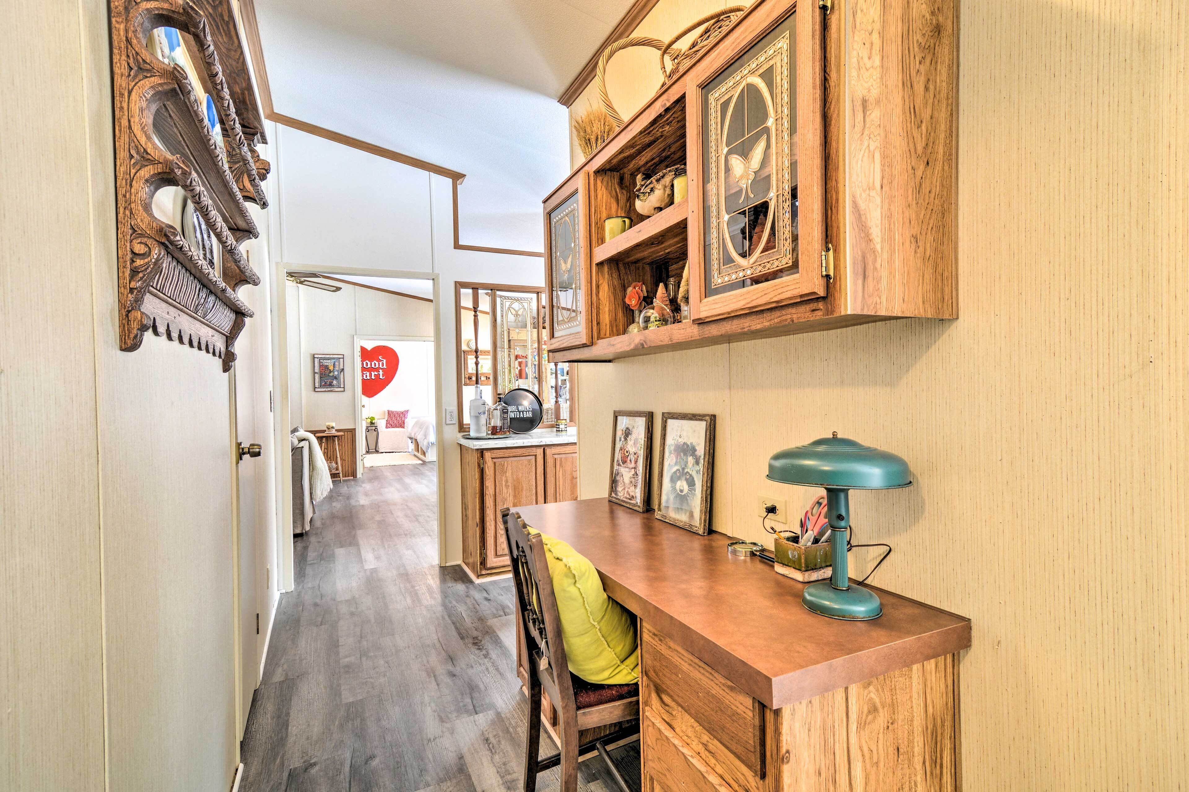 A hallway with wooden cabinets, a desk with a lamp, and a chair.