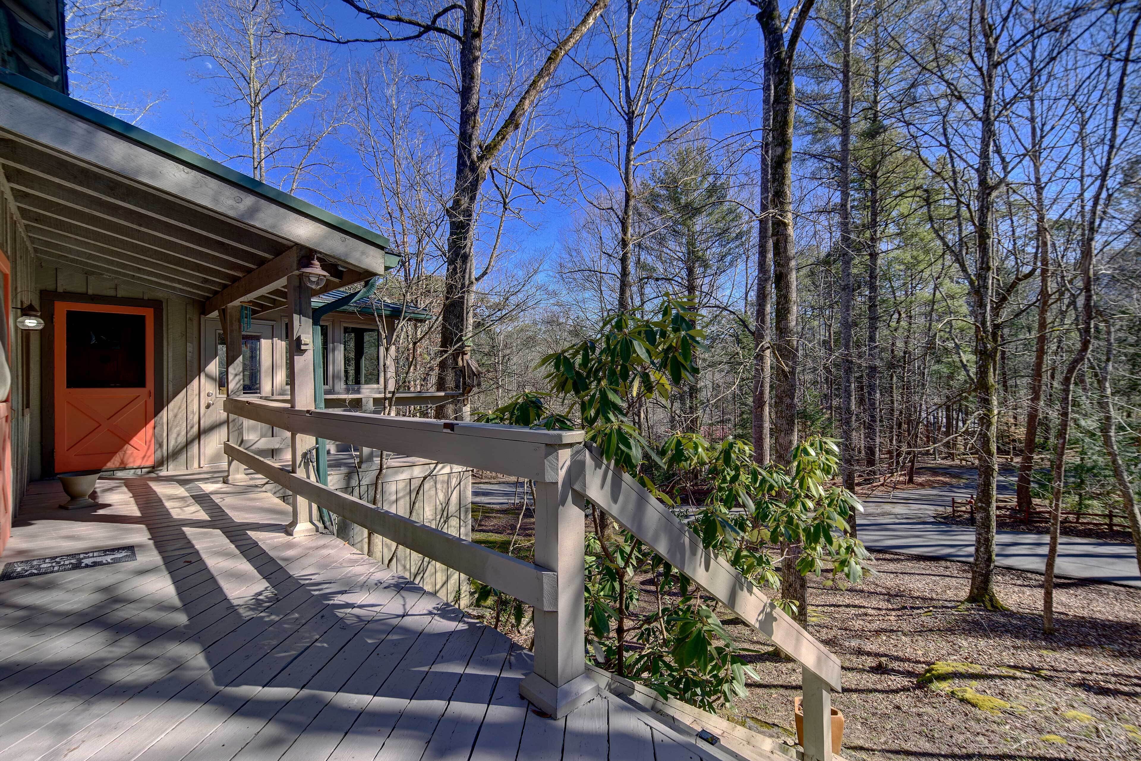 A wooden deck leading to a building with a red door, surrounded by trees.