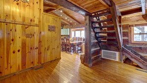 A wooden interior with a dining area, a staircase, and a sign that reads "HAPPY PLACE". - Cozy Log Cabin: 6 Mi to Great Smoky Mtns NP! (Townsend)