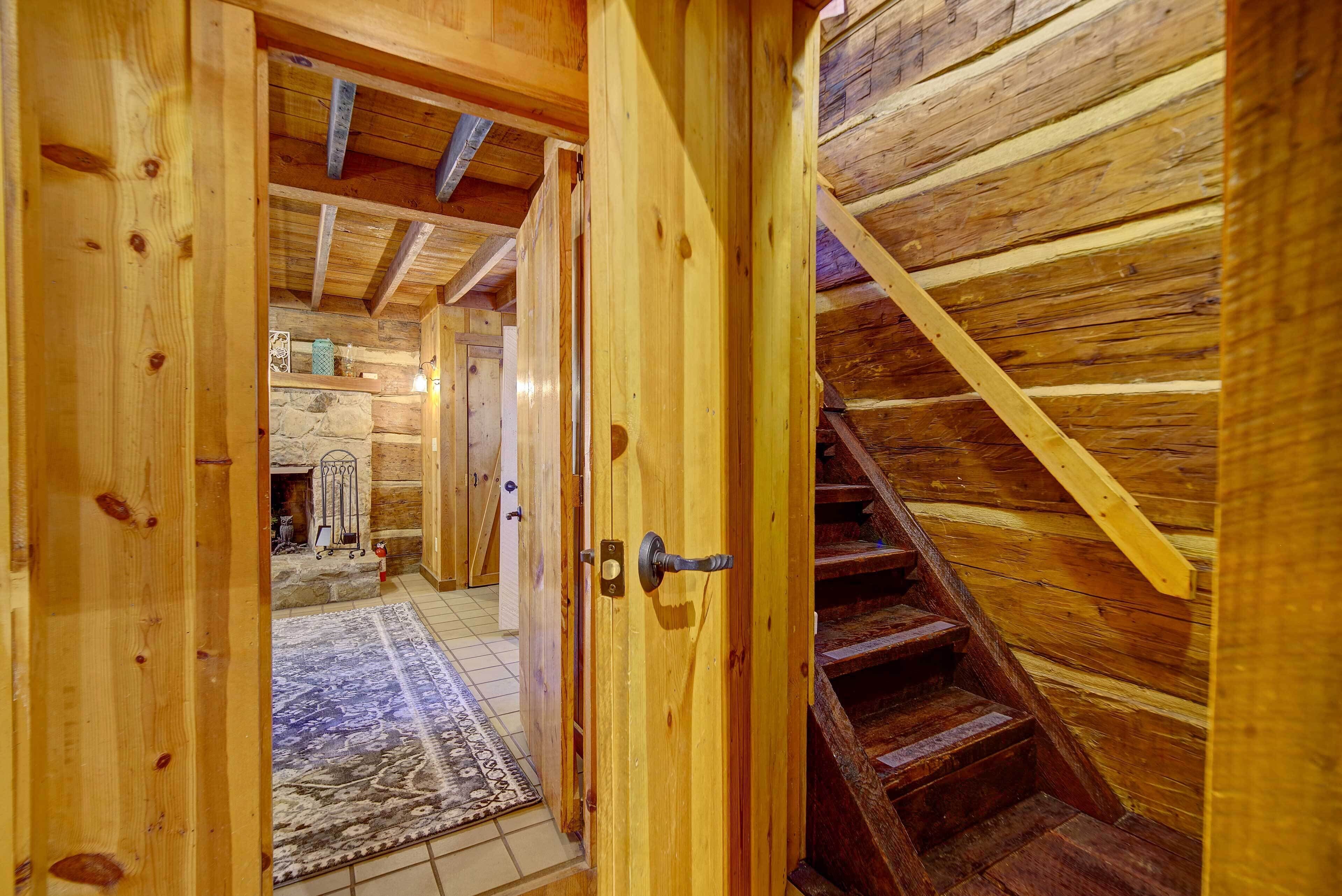 Un intérieur en bois avec un escalier, un tapis et une cheminée en pierre.
