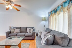 A living room with two grey sofas, a glass coffee table, a ceiling fan, and a floor lamp. - Glendale Heights Home With Office and Backyard! (Glendale Heights)