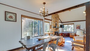 A spacious dining area with a wooden table and metal chairs, a stone fireplace, and large windows offering views of the outdoors. - Near Skiing: Lakefront Gem w/ Kayaks in Long Pond (Long Pond)