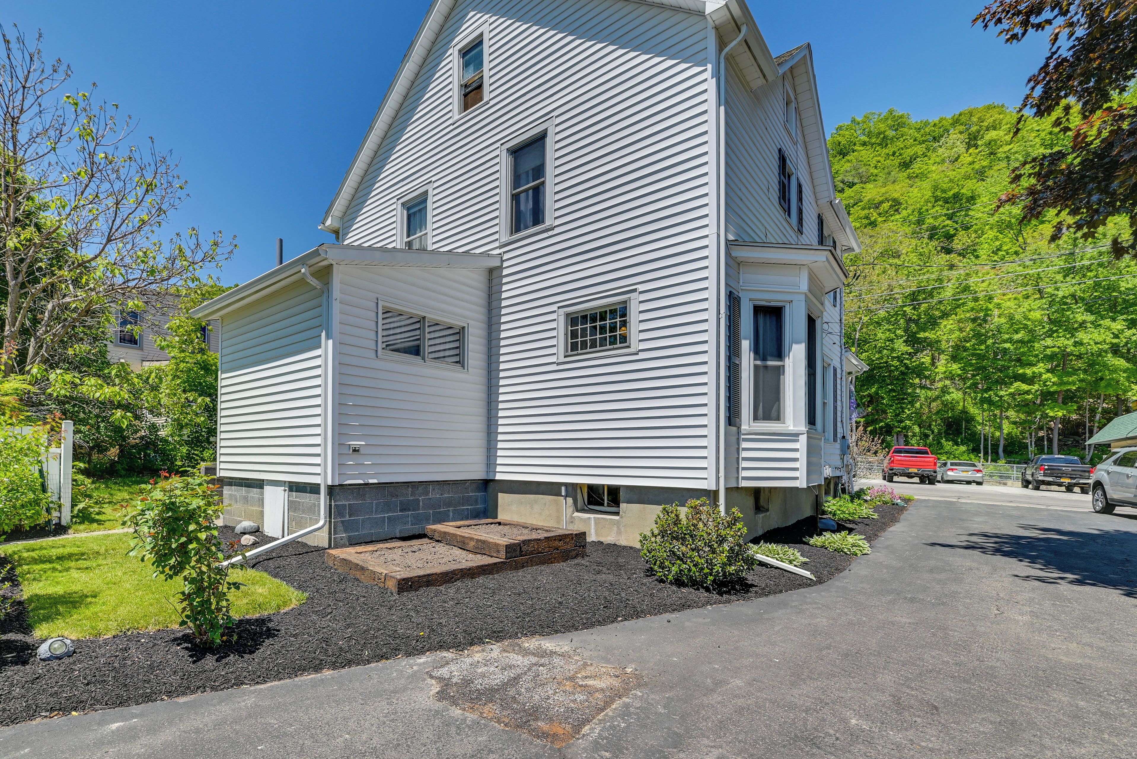 A two-story house with a front porch, a small garden, and a driveway.