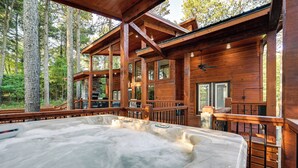 A wooden cabin with a hot tub and a deck overlooking a forest. - Sleek Cabin w/ Hot Tub: 11 Mi to Broken Bow Lake! (Broken Bow)