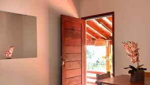 Una mesa de comedor de madera con sillas, una puerta de madera con un número y una lámpara colgante.