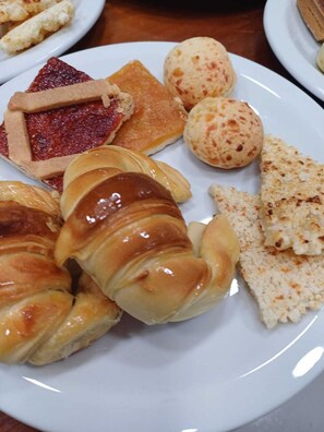 Une assiette contenant divers pâtisseries, notamment un croissant, une tarte et quelques petits pains ronds.