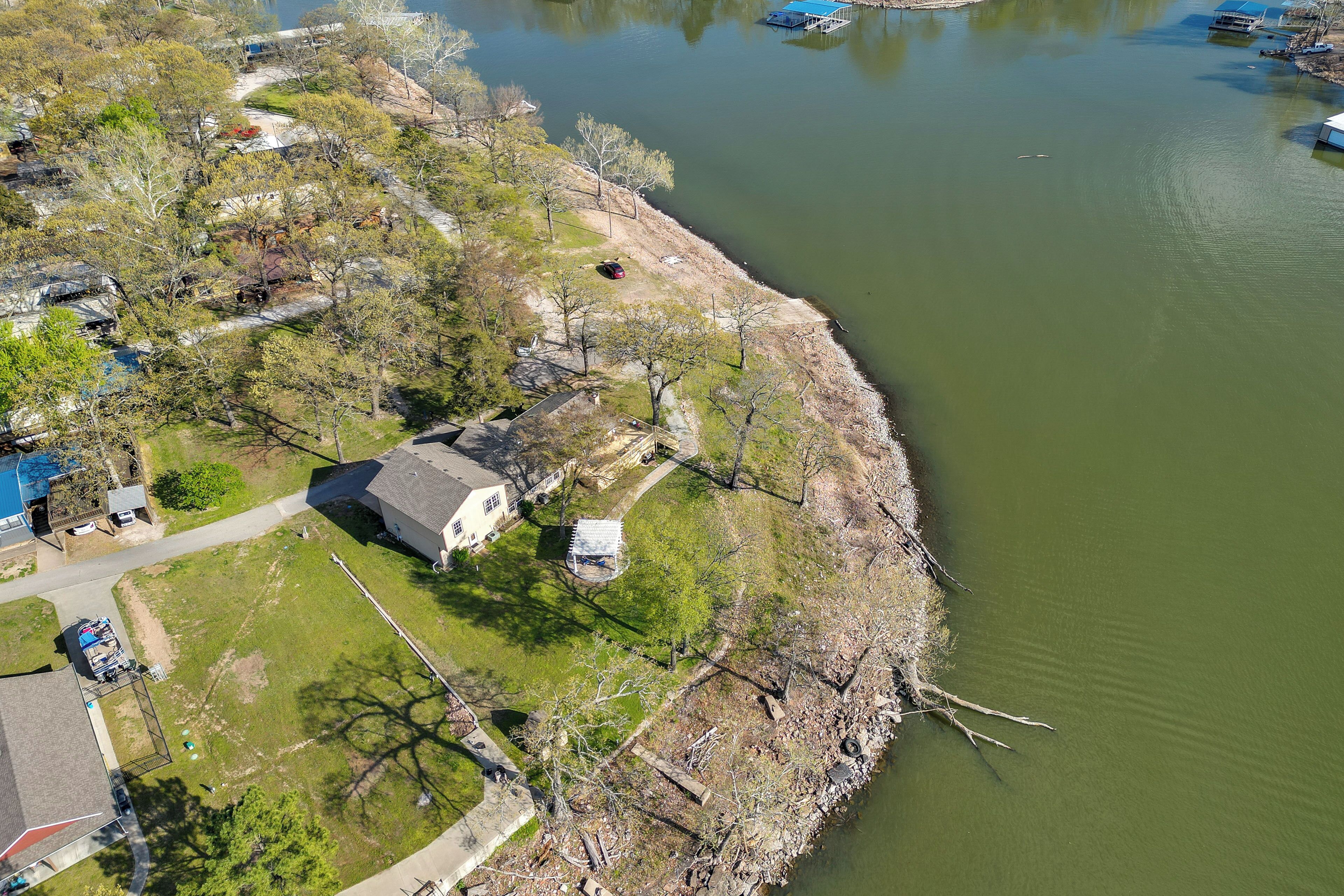 An aerial view of a lakeside property with a house, a dock, and boats.