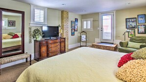 A bedroom with a large bed, a dresser, a television, and a window with blinds. - Walkable Downtown Logan Apartment w/ Rooftop Deck (Logan)