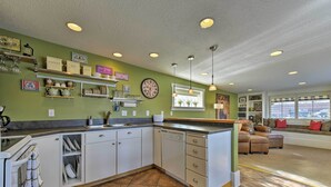 A kitchen with white cabinets, a dishwasher, and a sink. There are shelves with kitchenware and a clock on the wall. - Walkable Downtown Logan Apartment w/ Rooftop Deck (Logan)