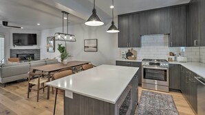 A modern kitchen with a central island, dark wood cabinets, stainless steel appliances, and pendant lighting. - Chic & Sunny Provo Townhome w/ Rooftop Deck! (Provo)
