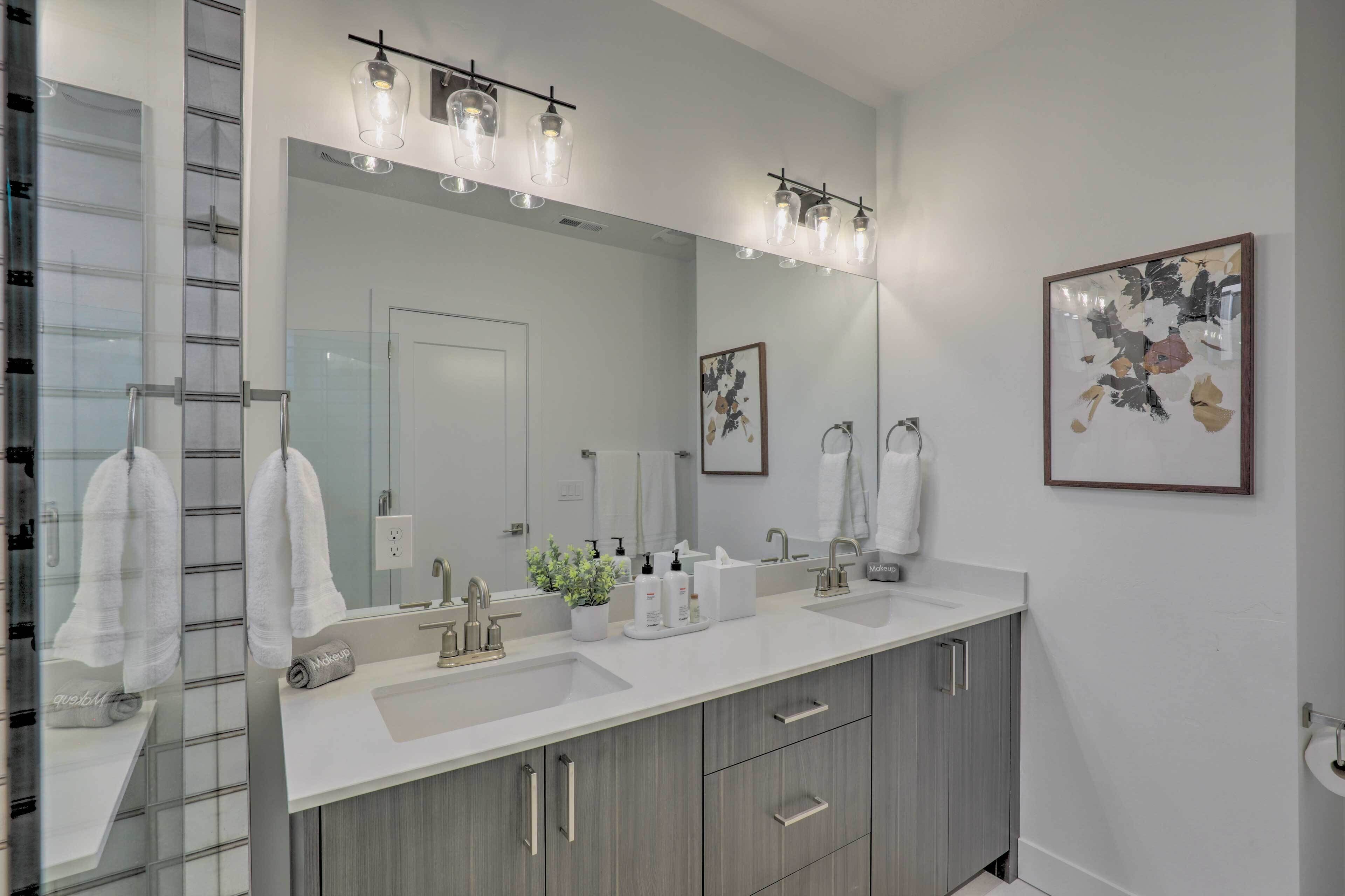 A modern bathroom with two sinks, a large mirror, and a towel rack.