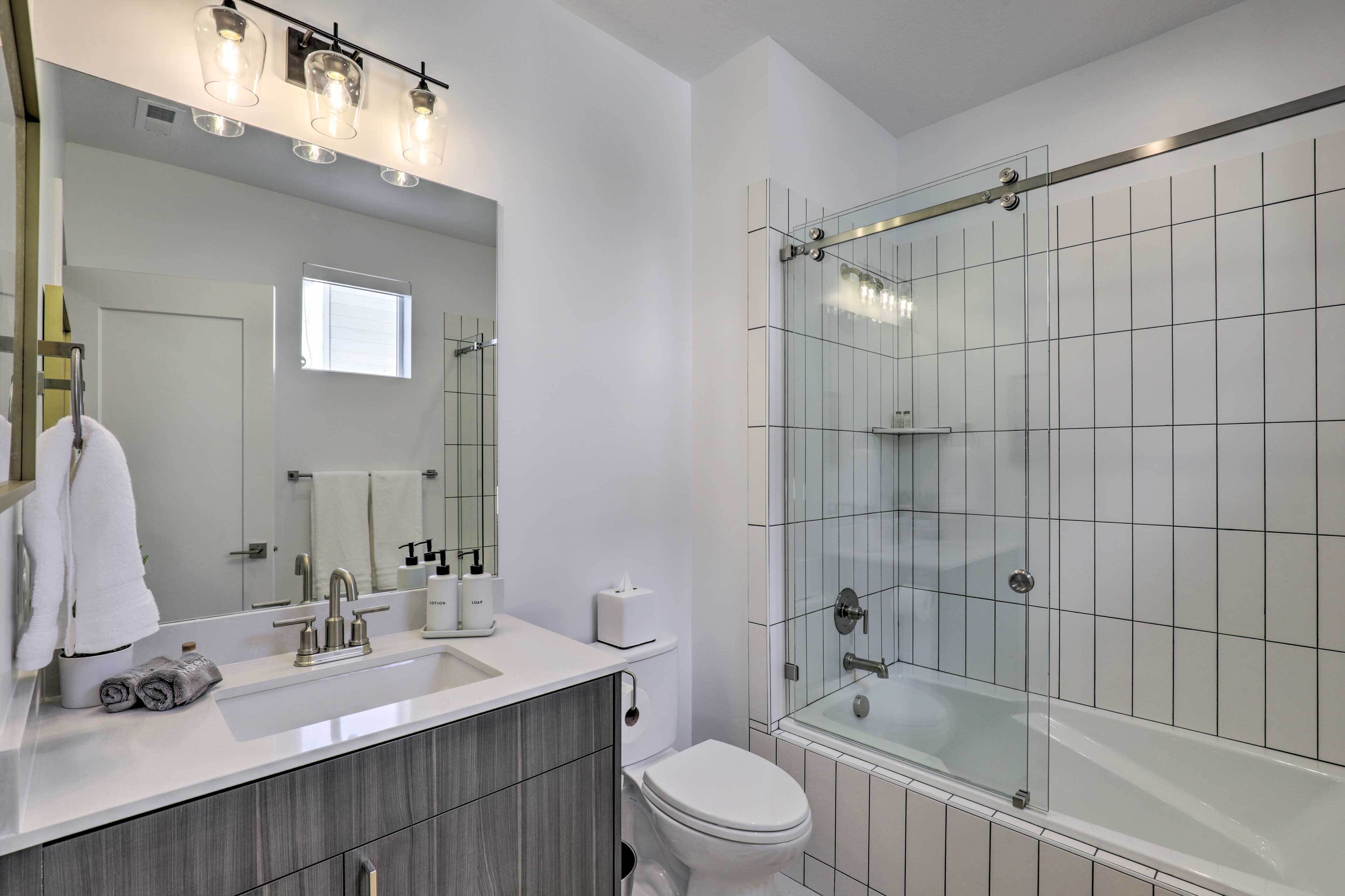 A modern bathroom with a glass shower enclosure, a vanity with a sink, and a toilet.